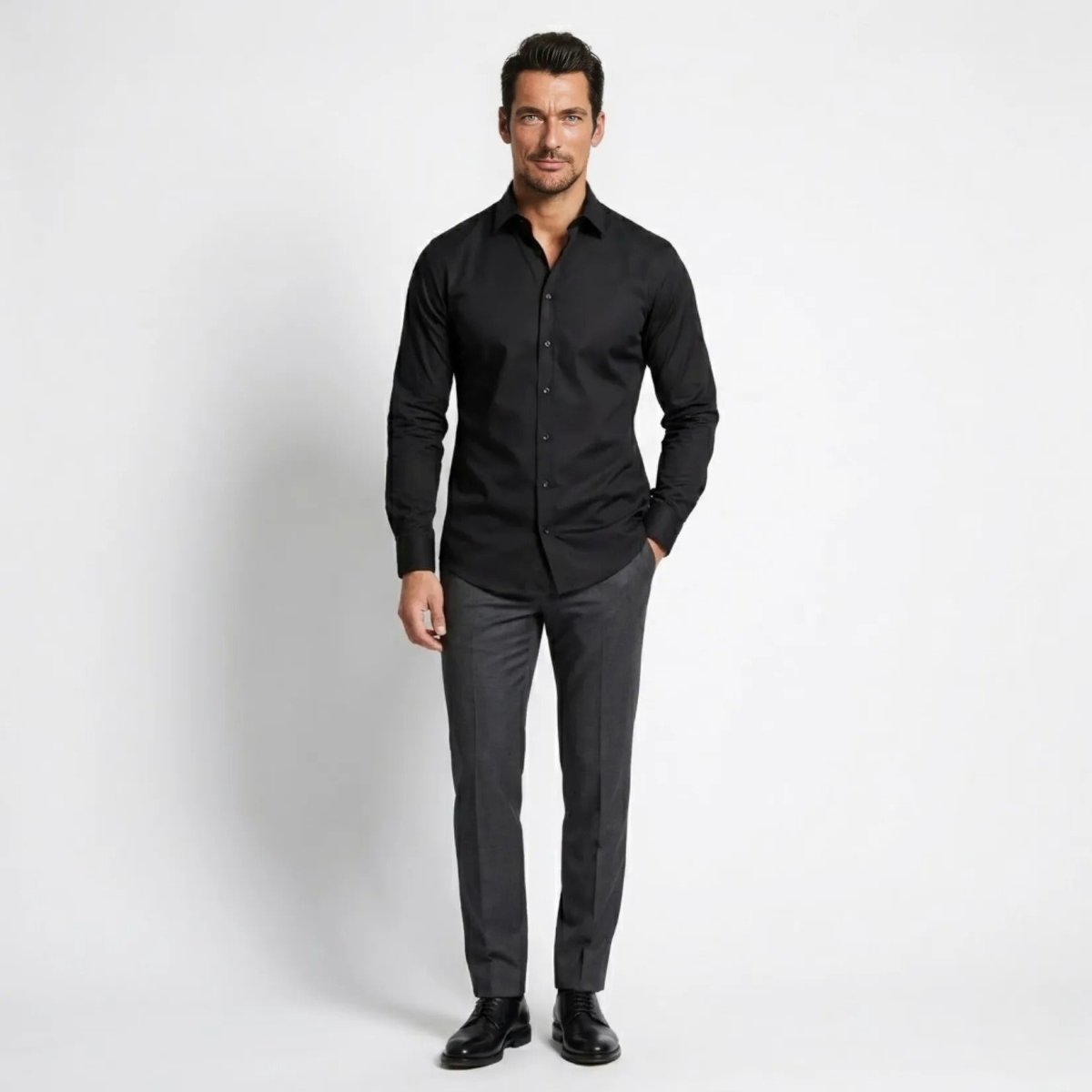 Front view of male model wearing a premium tailored fit black dress shirt with grey dress pants by Kouvr.