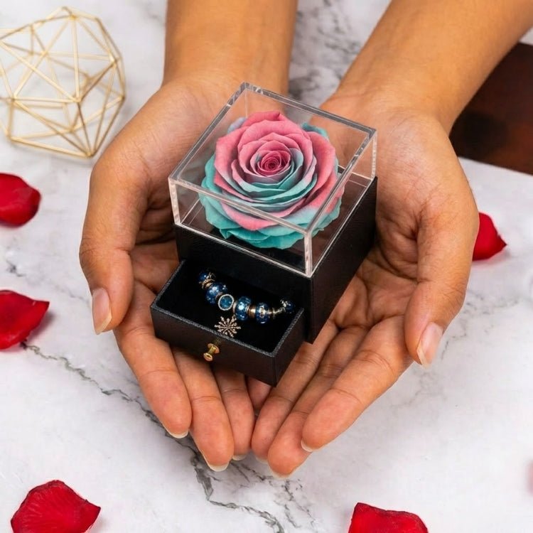 Hands holding a unique pink and teal ombre eternal rose gift box, showcasing the clear acrylic lid and the jewelry compartment.