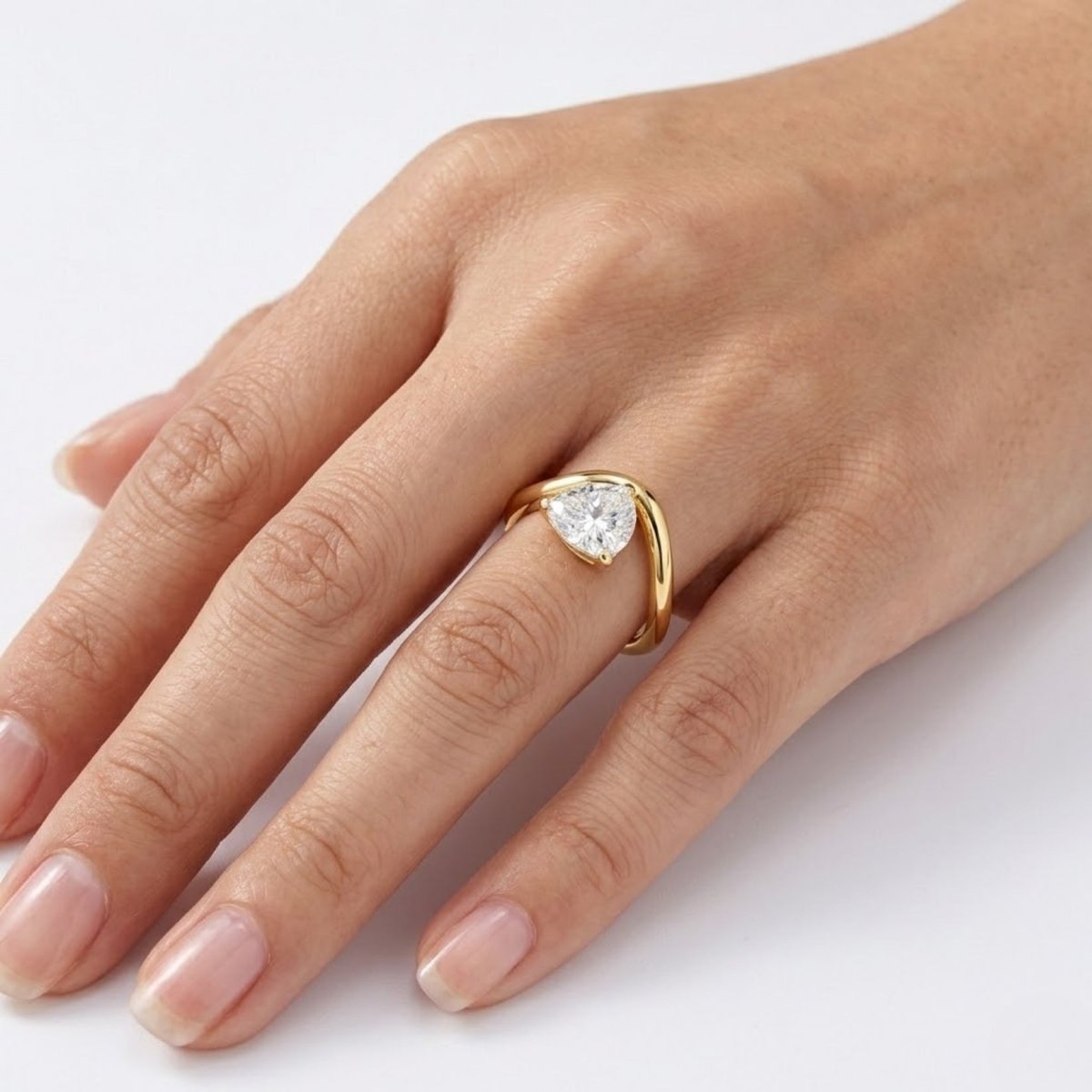 Top-down view on a hand of the Kouvr Zuri sculptural pear diamond ring in 18k yellow gold.