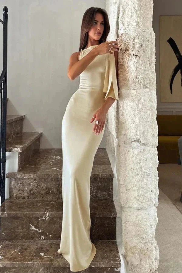 Model wearing the Kouvr Fashion Reese one shoulder satin gown in champagne ivory on a marble staircase