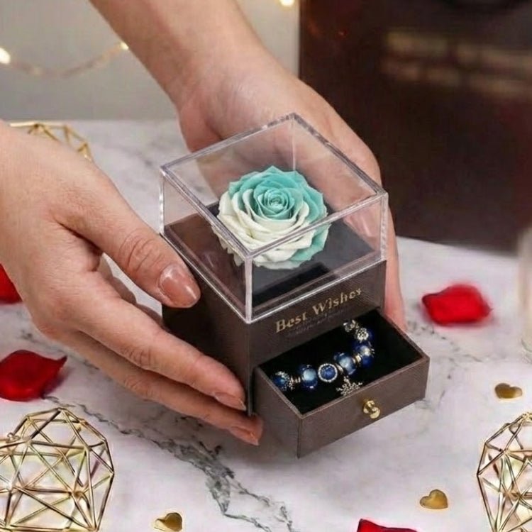 Hands presenting a teal and white gradient forever rose box, focusing on the detailed rose petals and the crystal-clear display case.