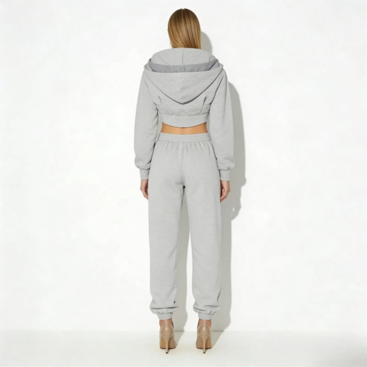  kouvr-fashion-ellaine-corset-zip-
Back view of a model in the Kouvr Fashion ellaine heather grey sweatsuit, highlighting the hood detail and structure of the cropped hoodie. 