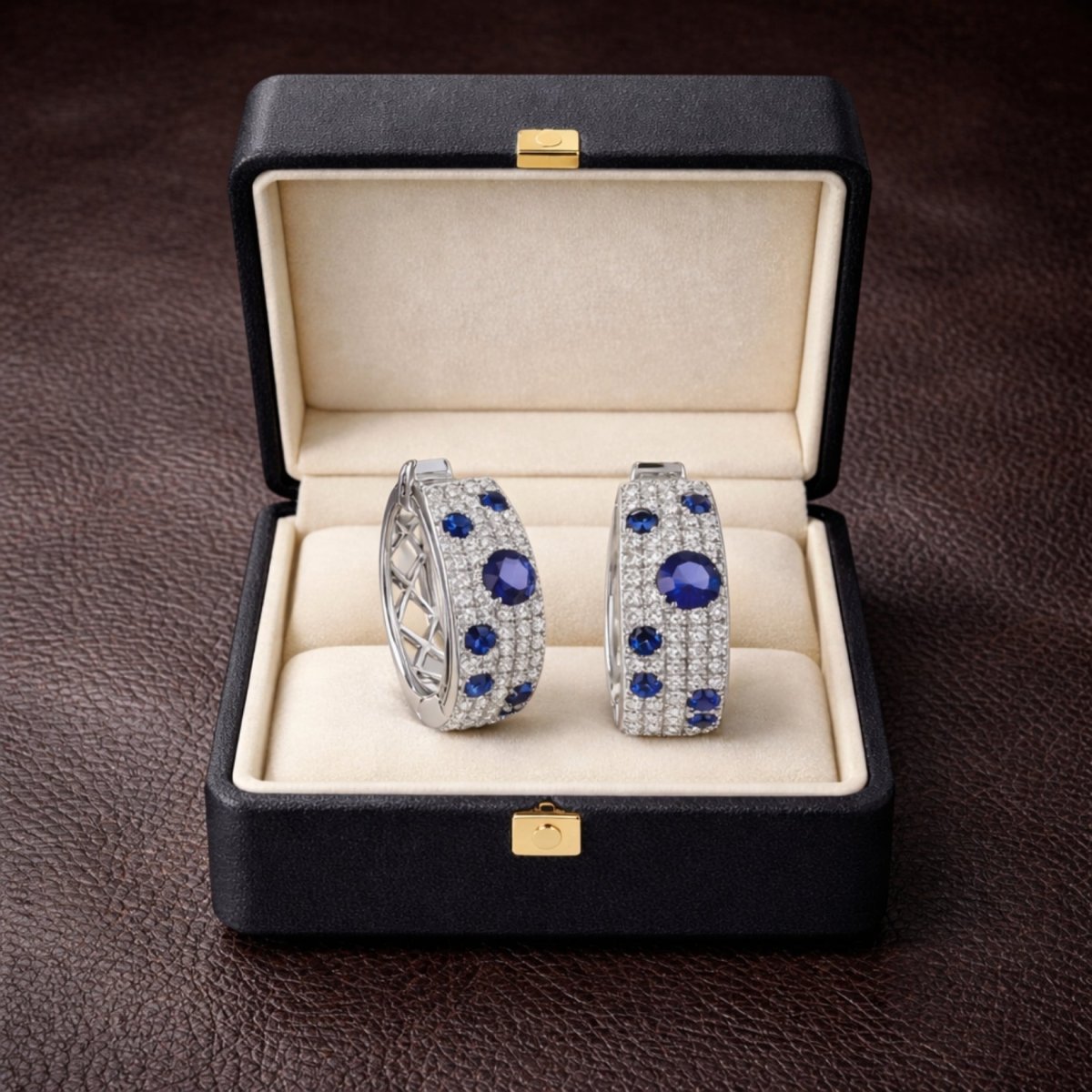 The Kouvr Amaris  pavé diamond and sapphire earrings presented inside a luxurious black leatherette jewelry box with a cream interior.