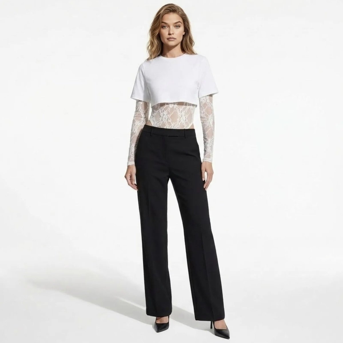 Model wearing the Angelique white layered t-shirt bodysuit with sheer lace sleeves, paired with black tailored trousers. Front view.