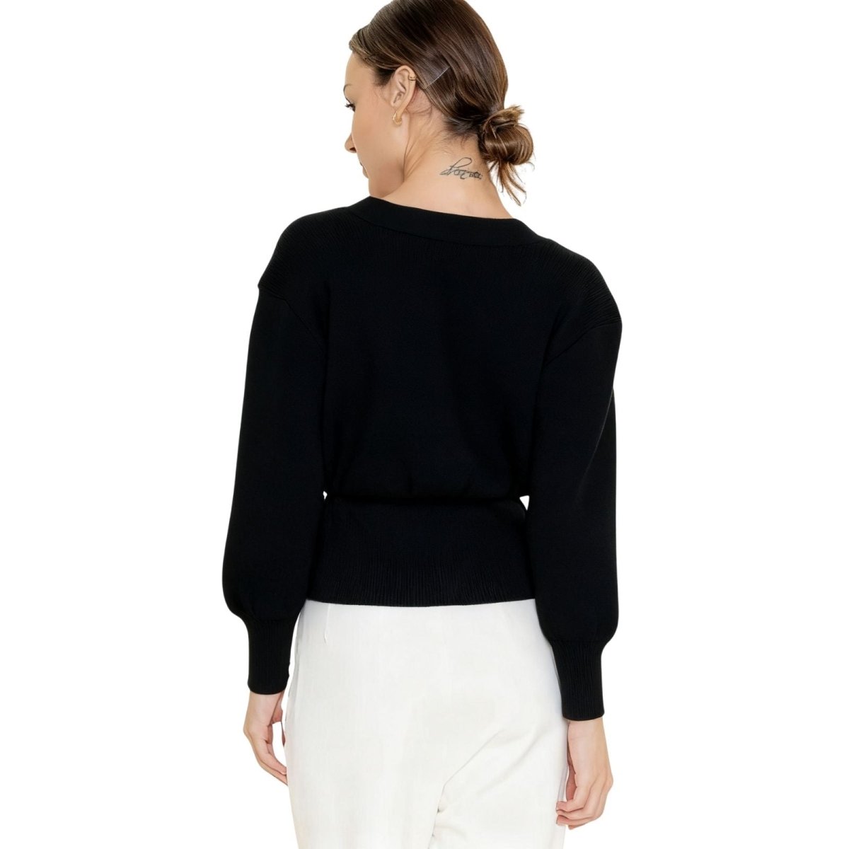 Model wearing a black kouvr cardigan and white pants on a white background
