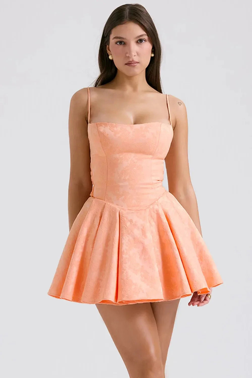 Model wearing Kouvr Ayliah peach jacquard mini dress with large bow detail at the back