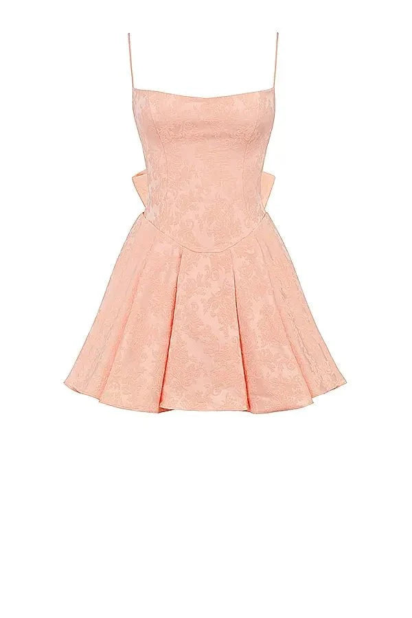 Model wearing Kouvr Ayliah peach jacquard mini dress with large bow detail at the back