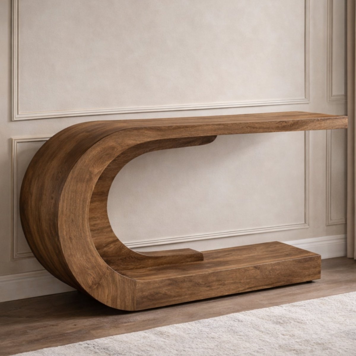 The Kouvr C-shaped sculptural wood console table shown in a minimalist entryway against a white paneled wall.