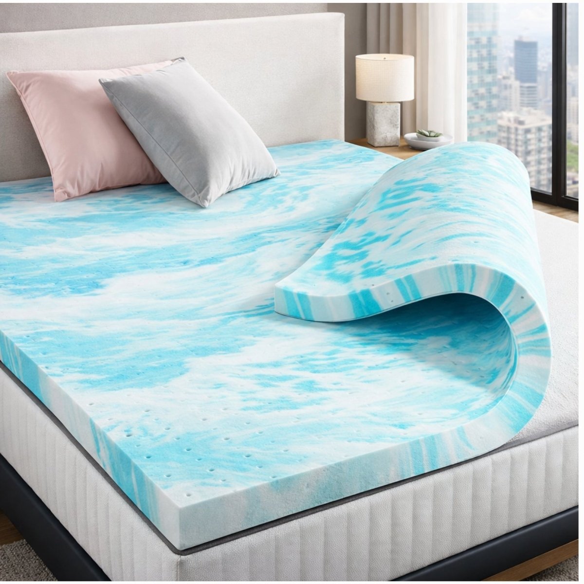 Kouvr cooling gel memory foam mattress topper rolled up on a bed, showing blue swirl cooling infusion and ventilated texture for airflow.