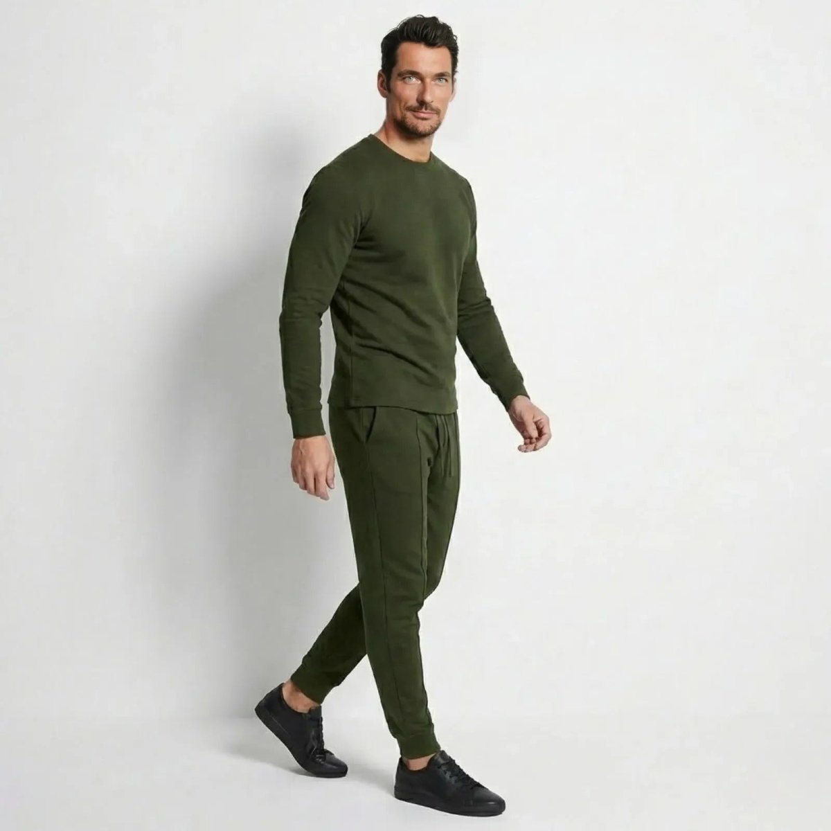 Man in profile wearing the army green Kouvr Crue crewneck and tapered jogger set, showing the athletic fit.
