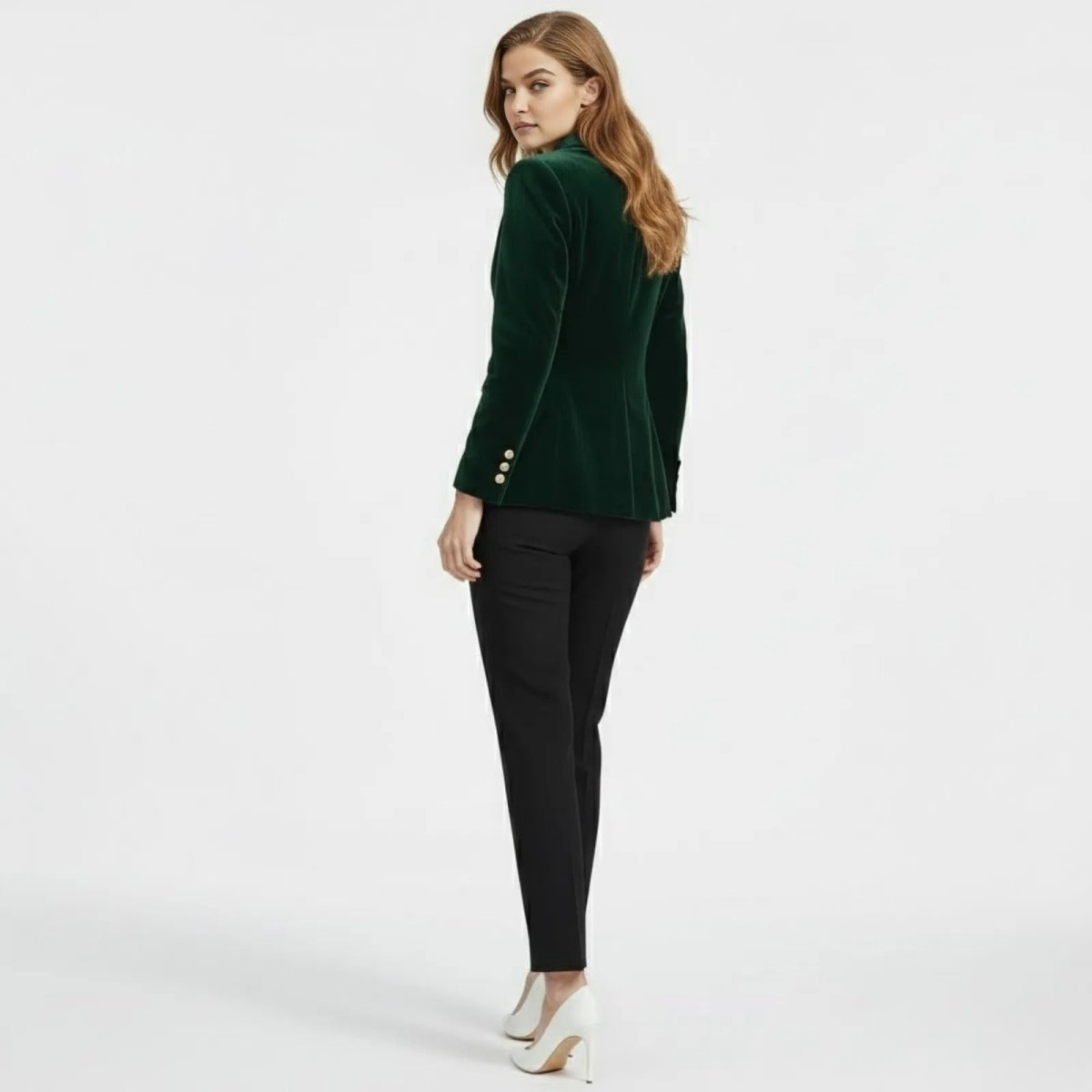 Back view of a model wearing the Kouvr tailored green velvet blazer, looking over her shoulder.
