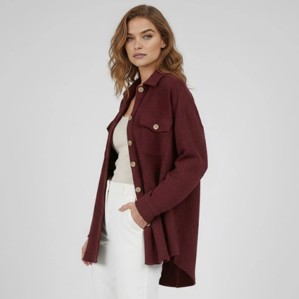 Side profile of a model in the burgundy Donna shirt jacket, highlighting the high-low hem and long sleeve silhouette.
