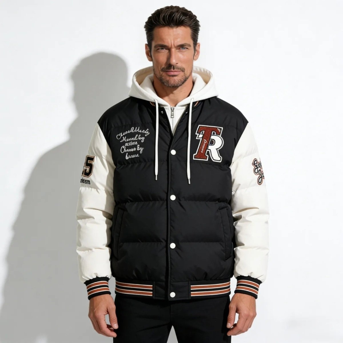 Model wearing the Kouvr Fashion 'Angelo' men's black hooded varsity puffer jacket, front view against a white background.