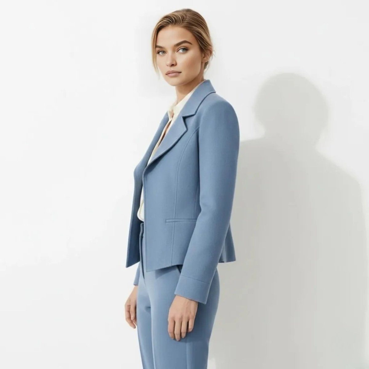 Side profile view of a woman in a tailored blue suit jacket showing its cropped length and structured fit by Kouvr Fashion.