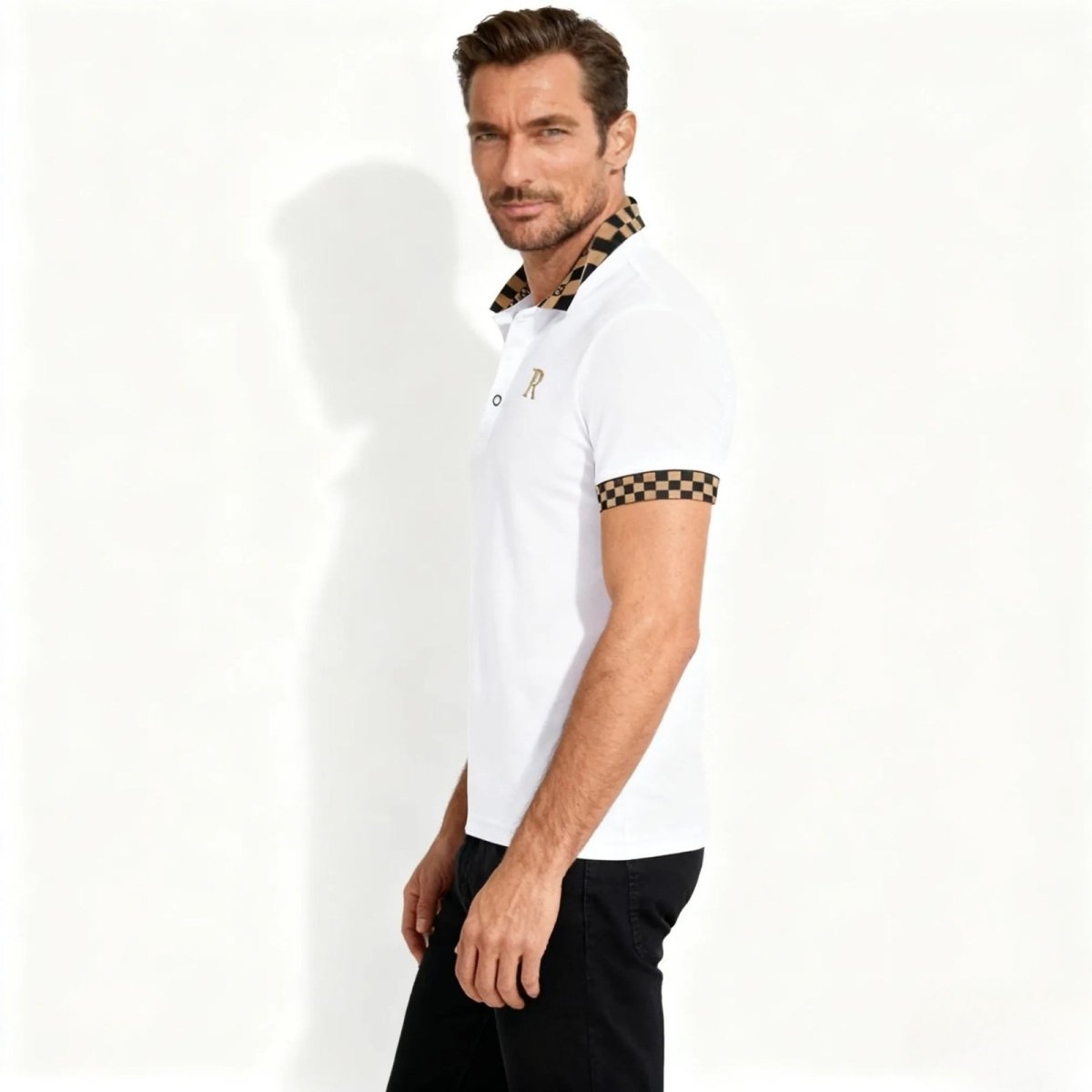 Side profile of a male model in the Kouvr Fashion white polo with checkered trim on the collar and short sleeve cuff, showing the slim fit.
