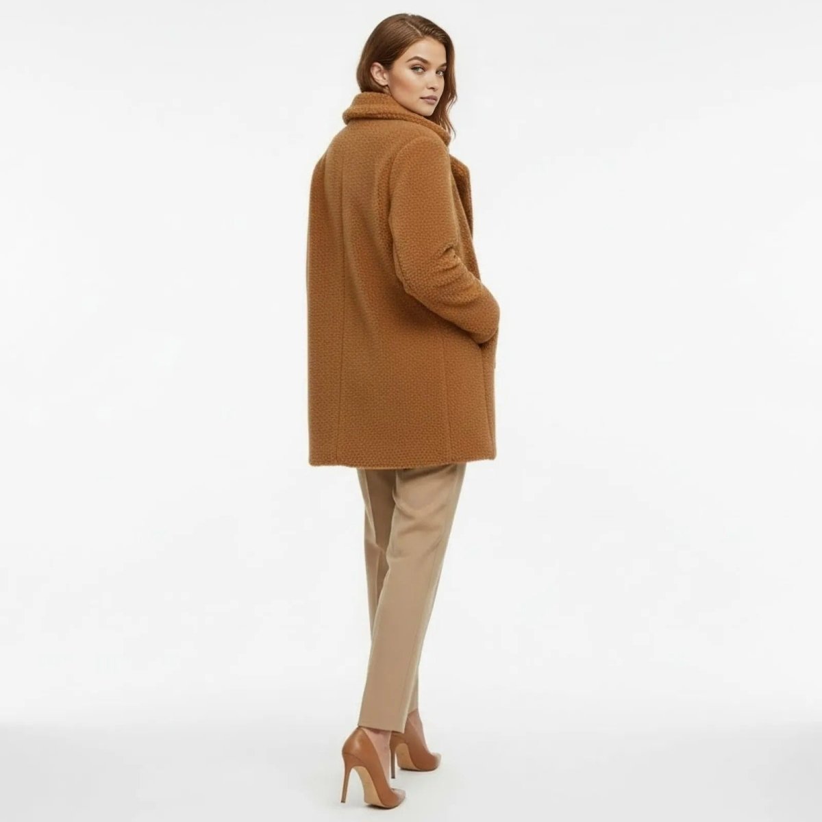 Back view of a woman wearing the Kouvr Fashion mid-length caramel brown sherpa coat, showcasing its silhouette and texture.
