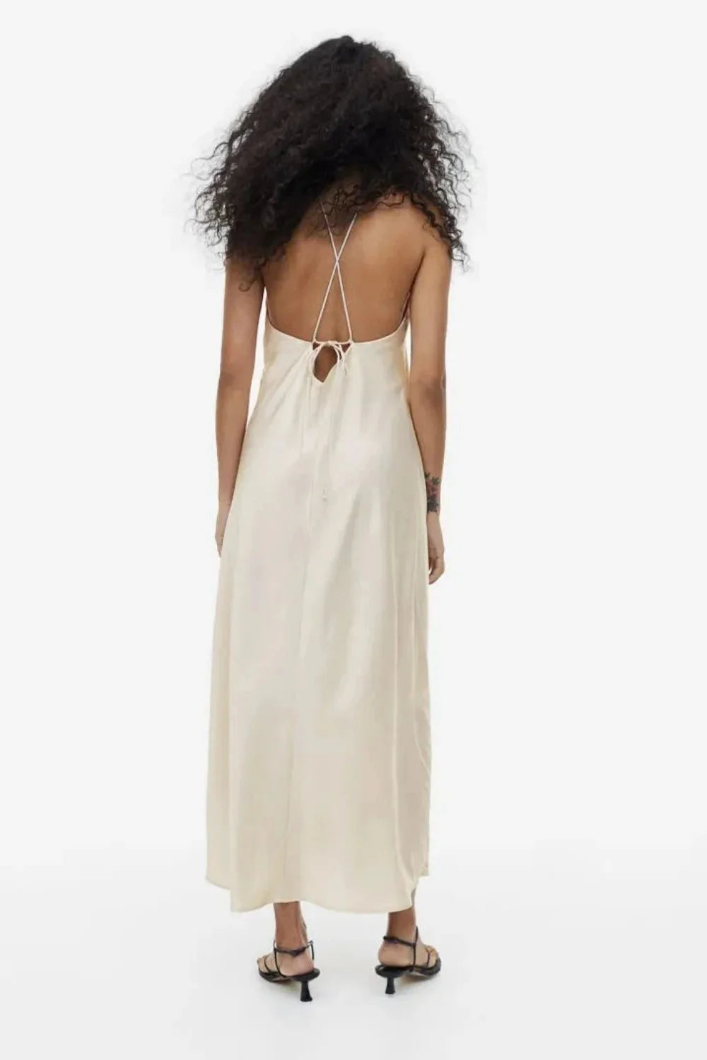 Model from behind wearing the Kouvr Fashion Cathalina beige satin halter dress showing the open back and criss-cross straps