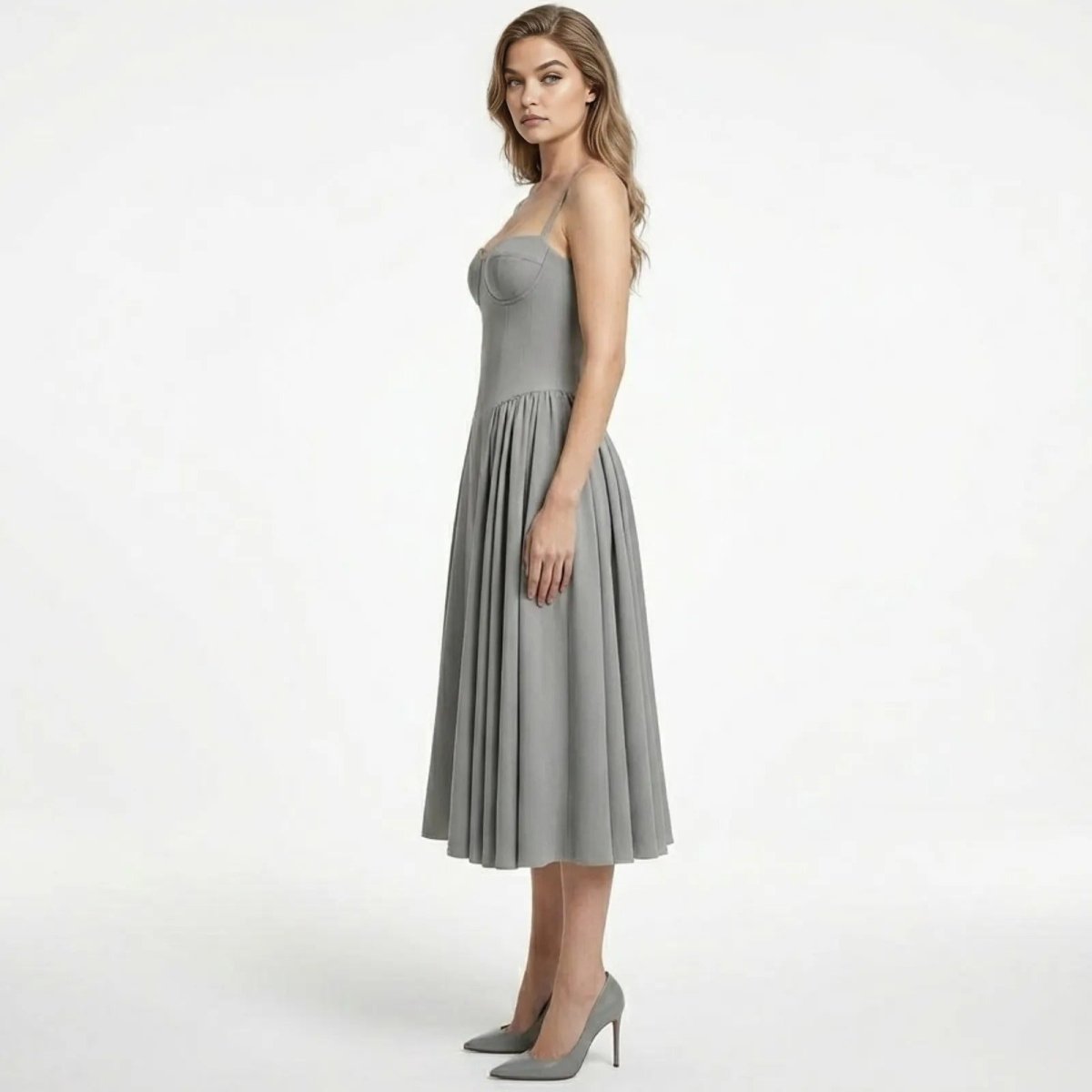 Side profile of a model in the Kouvr Fashion Evdokia grey midi dress, showcasing the fit-and-flare silhouette and structured bodice.
