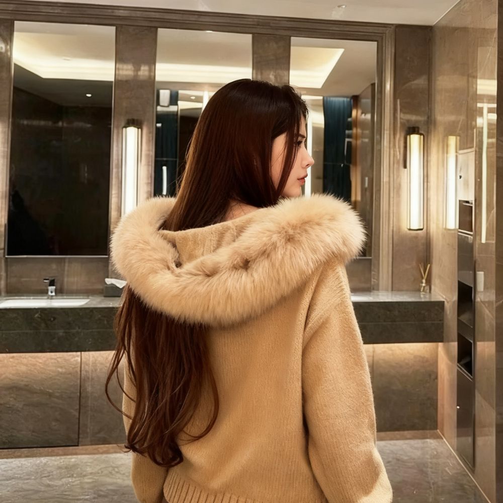 Woman wearing a brown kouvr coat with a fur collar in a modern bathroom.