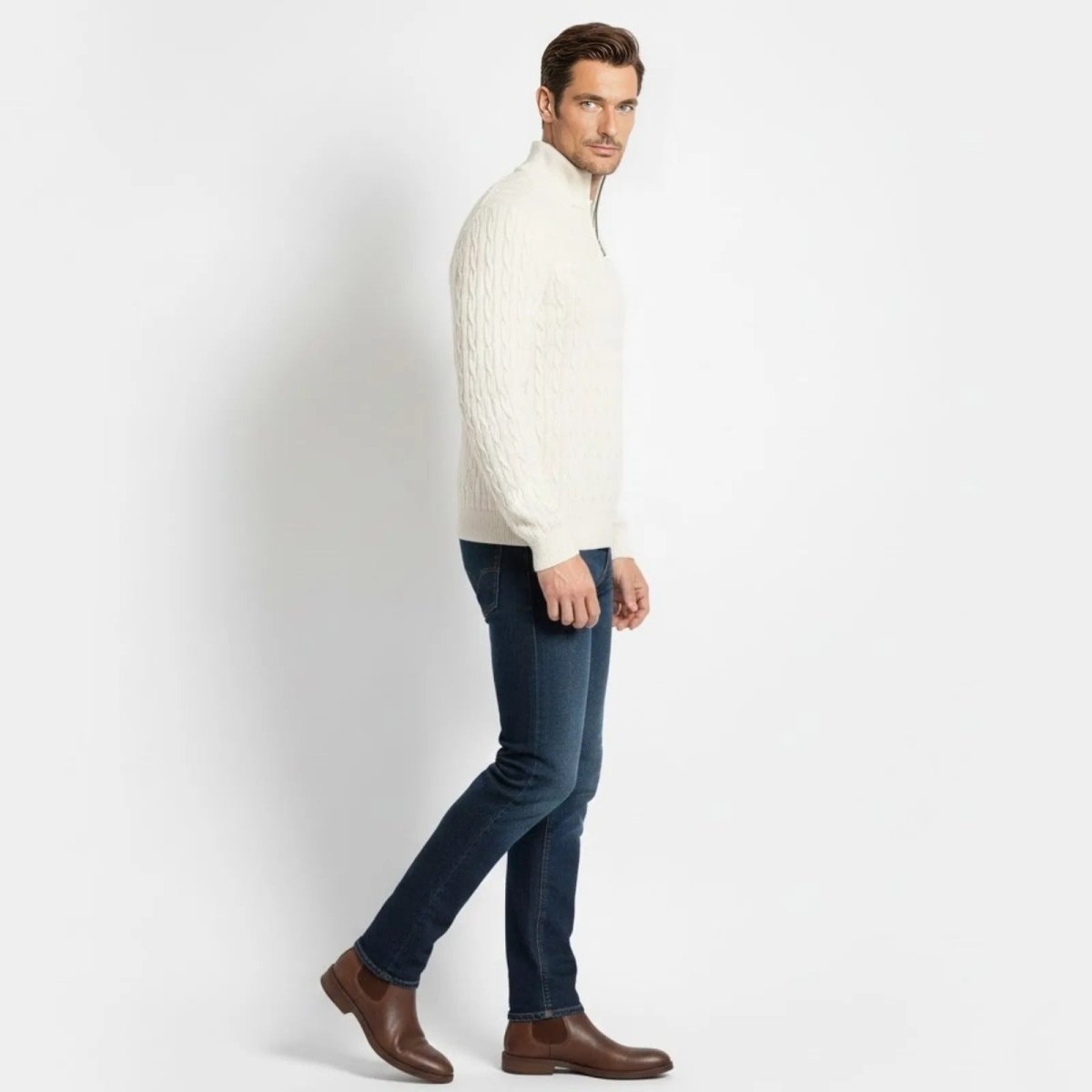 Male model in a side profile view walking, wearing the white cable-knit sweater, showing its fit and texture.