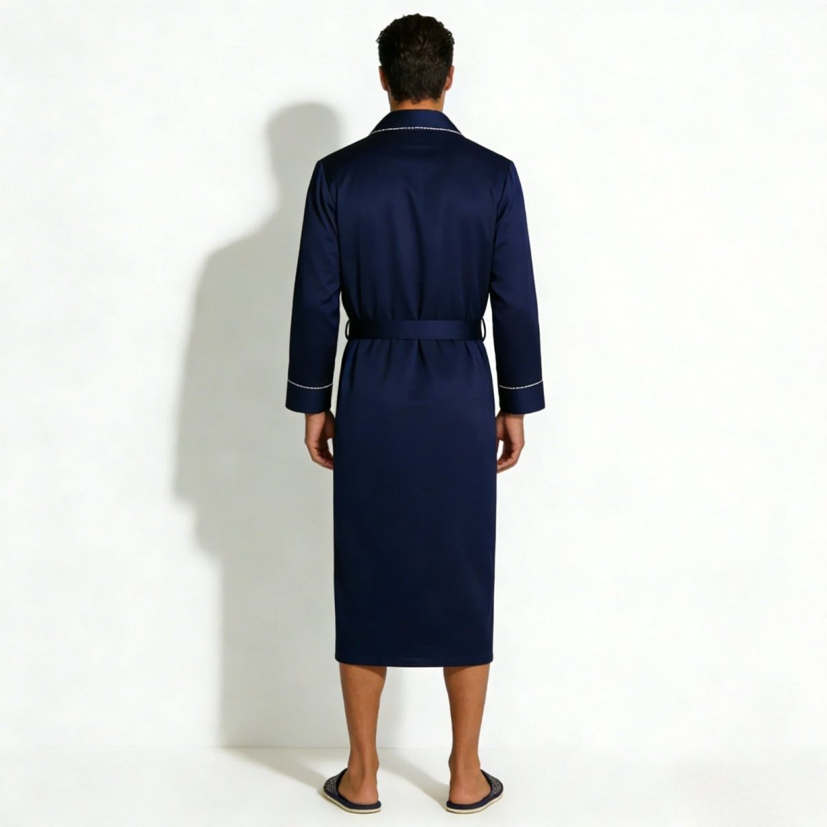 Back view of a man modeling a classic navy blue silk robe with a tie belt, showing the elegant drape of the fabric.