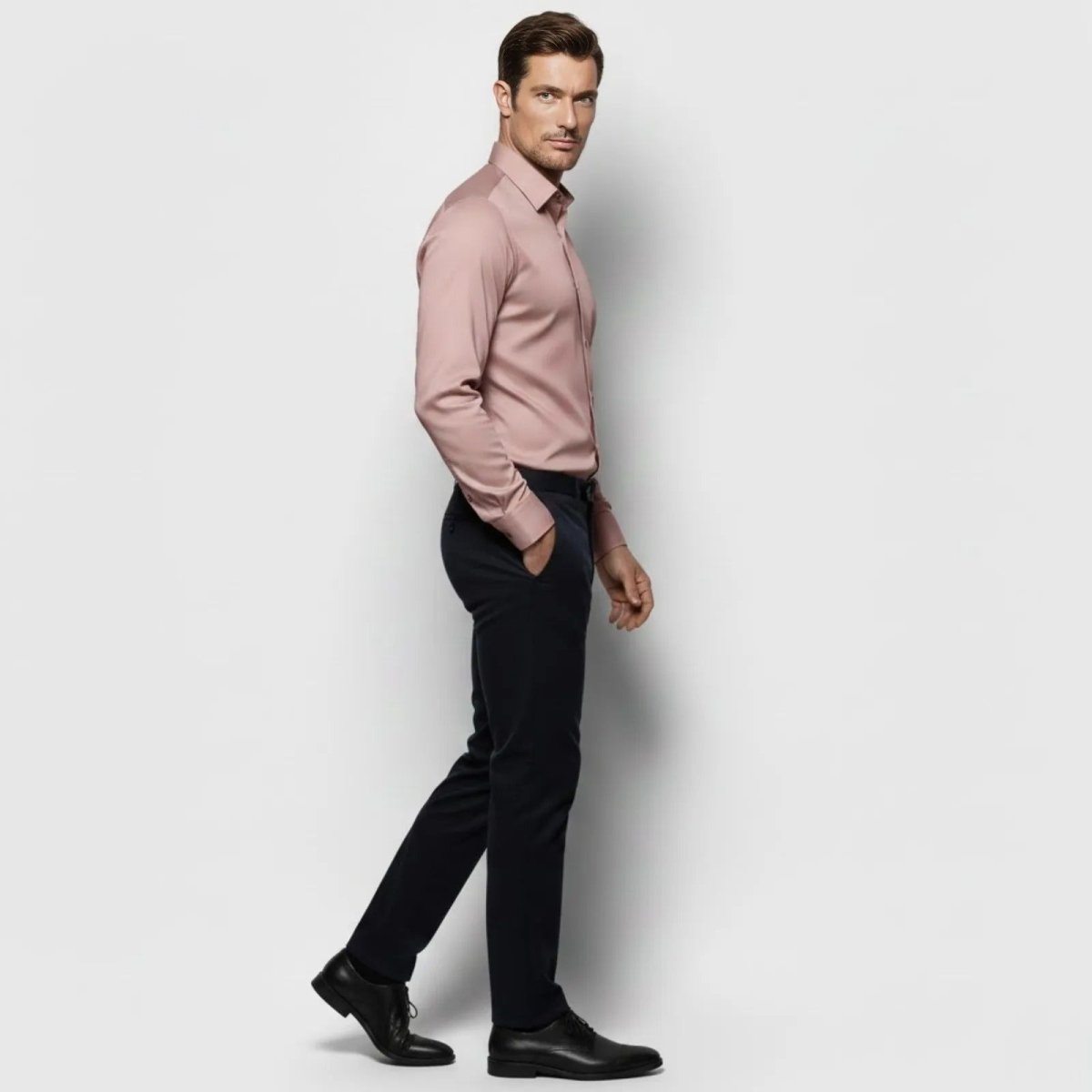 Side profile of a male model walking in a pink long sleeve business casual shirt, showcasing its tailored fit and drape.