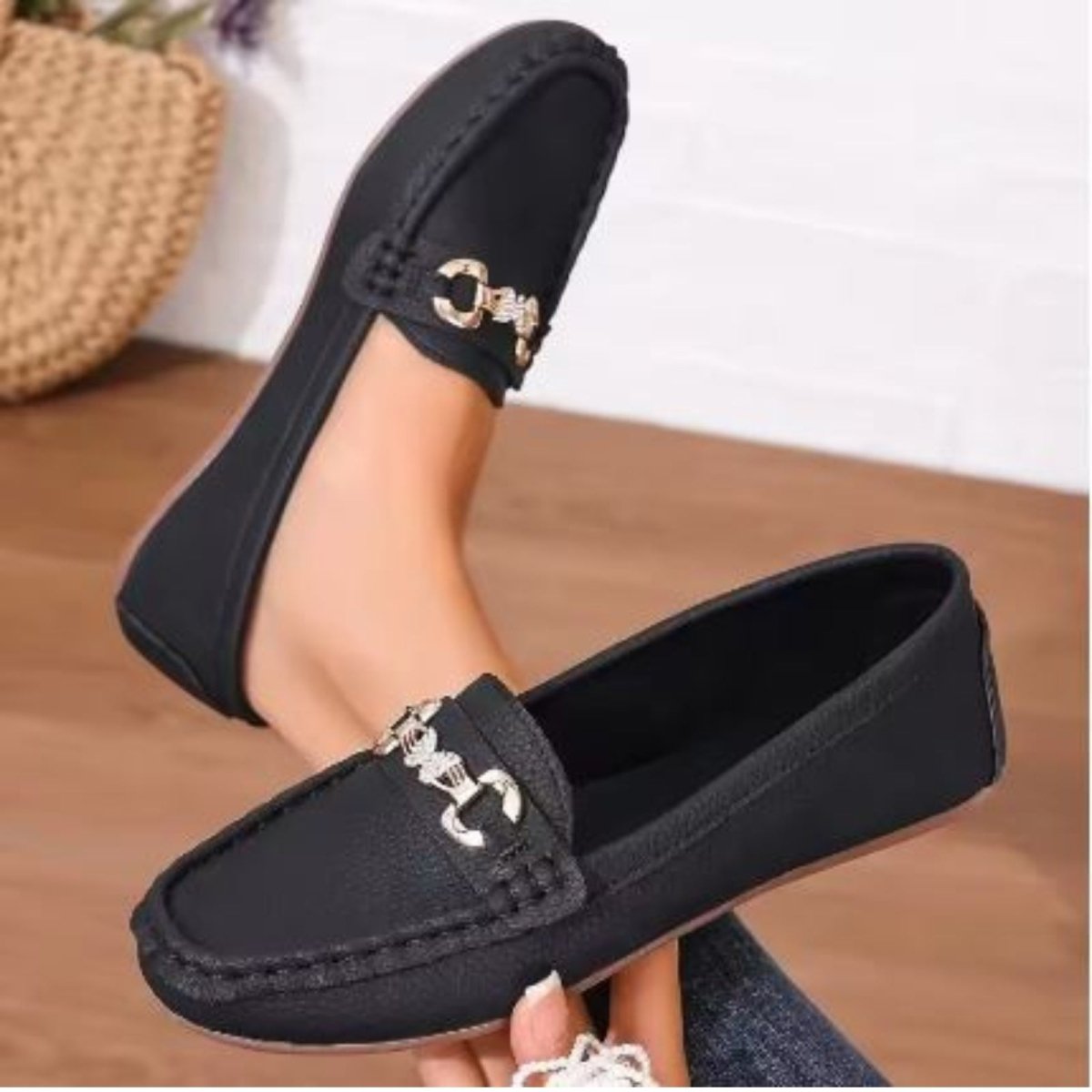A woman wearing Kouvr Mildred black leather horsebit loafers with cuffed blue jeans and a gold anklet.