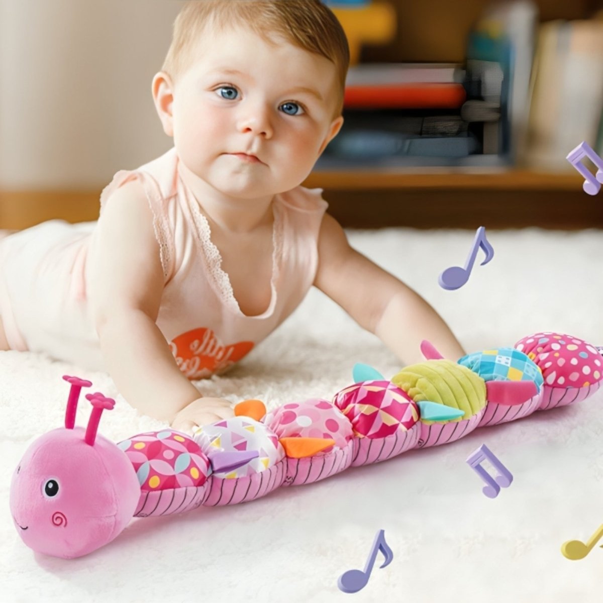 Baby playing with a colorful caterpillar toy on a bed
