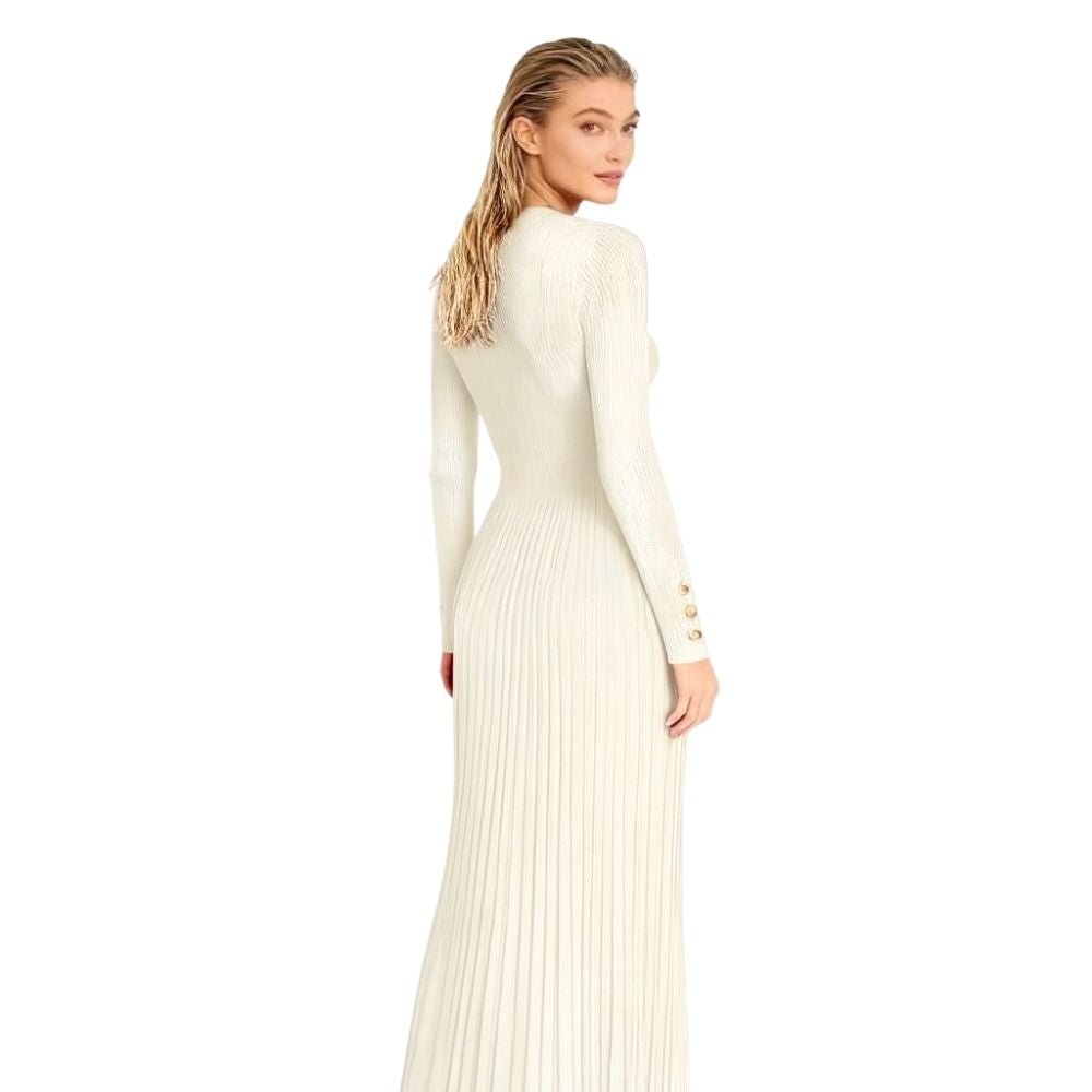 Model wearing the Kouvr Fashion long sleeve pleated knit maxi dress in cream, posing in a minimalist room
