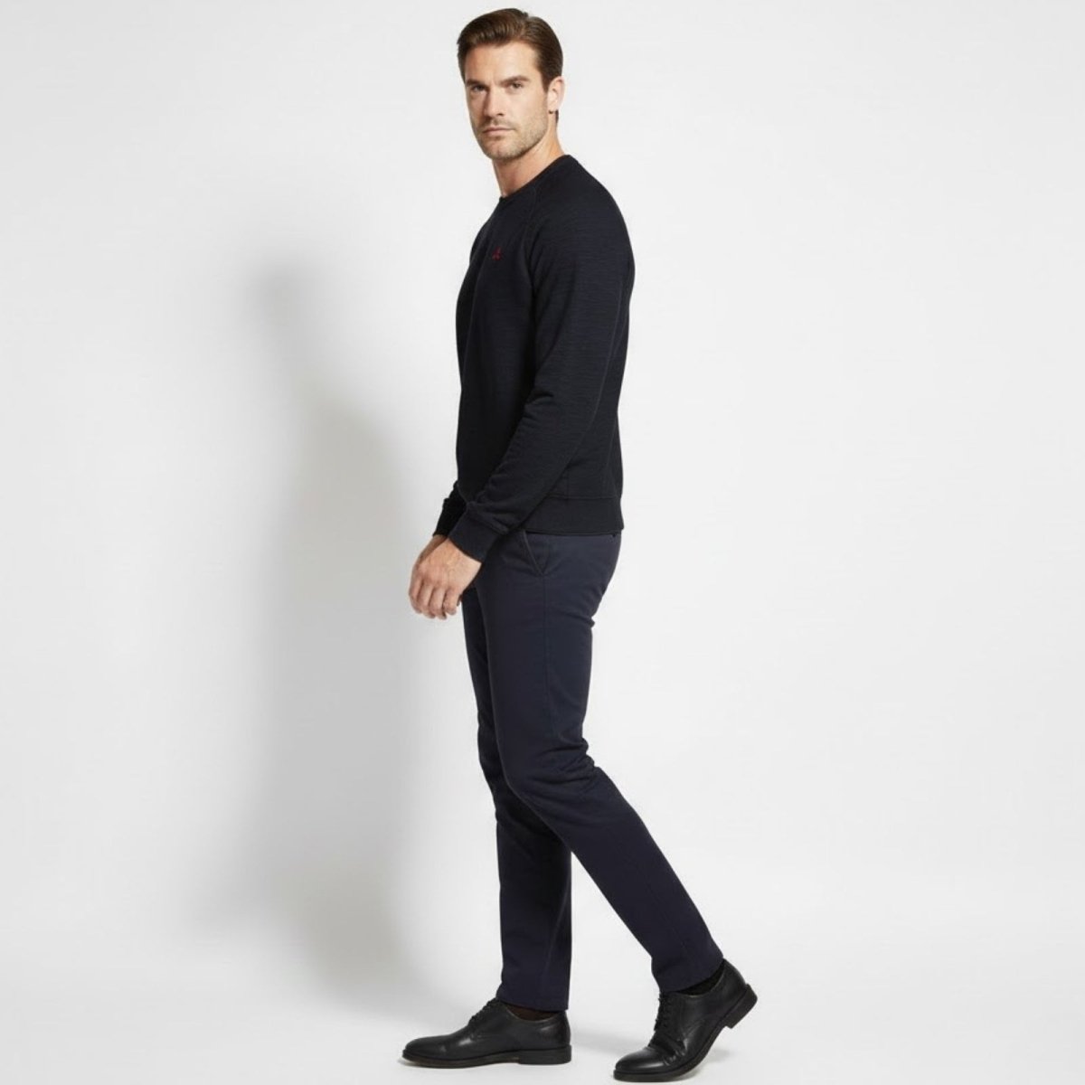 Male model in a side profile view wearing the Kouvr Fashion Deacon slim fit navy blue crewneck sweater, showcasing the fit and sleeve construction. 