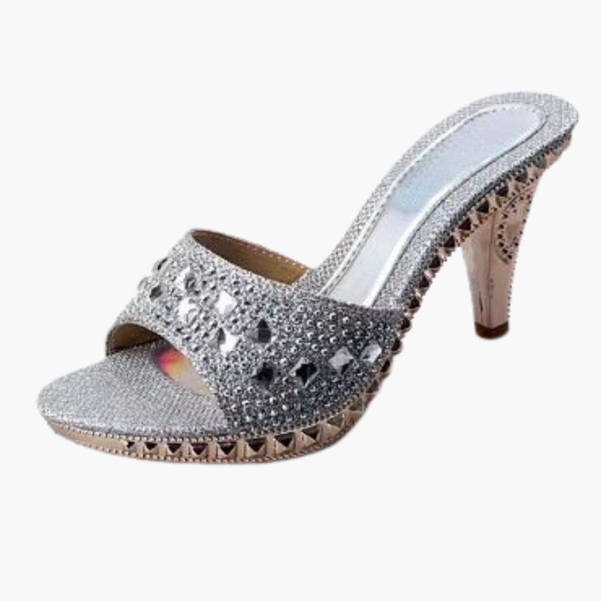 Side view of silver crystal embellished platform mule high heels with an ornate sculptural heel on a white background. 