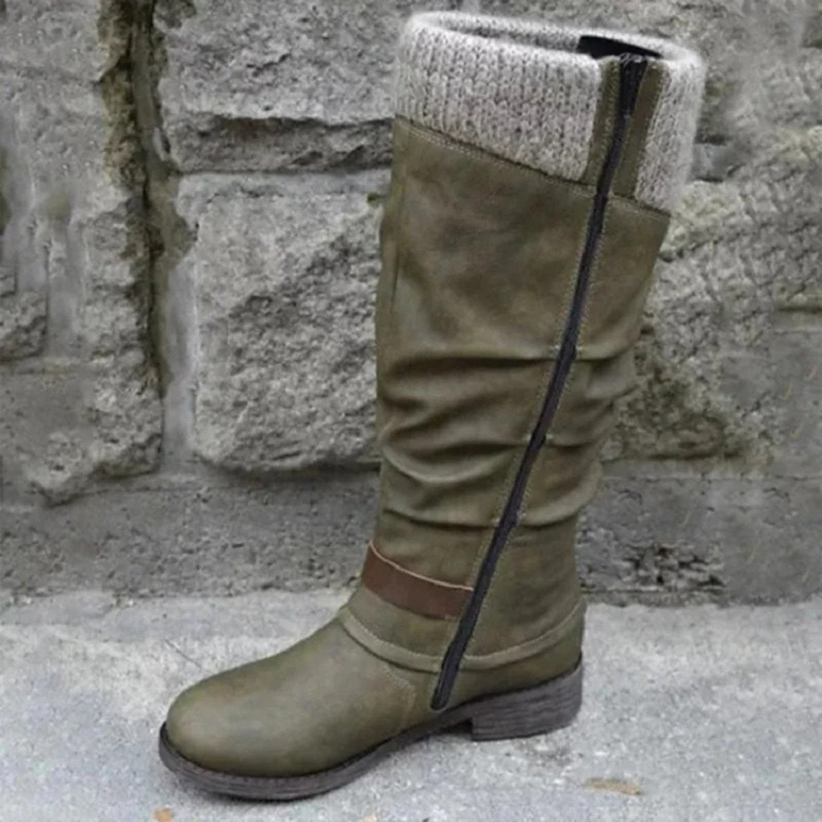 Green knee-high boot with knit cuff against a stone wall background