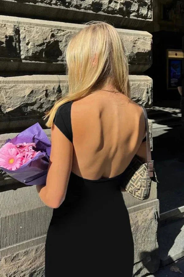 Model wearing the Kouvr Grace black boat neck maxi dress with a full view of the open back