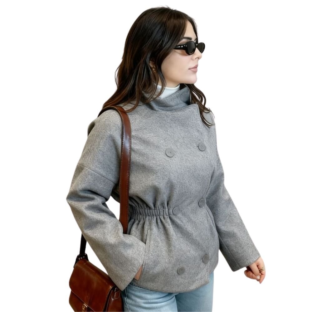 Side profile of a model wearing the Kouvr gray wool jacket with the waist cinched, highlighting its versatile shape and wide sleeves.