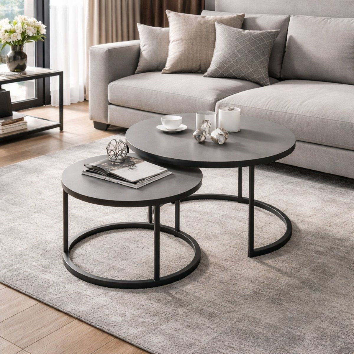 Grey stone top coffee tables styled with minimalist decor next to a light grey sectional sofa.
