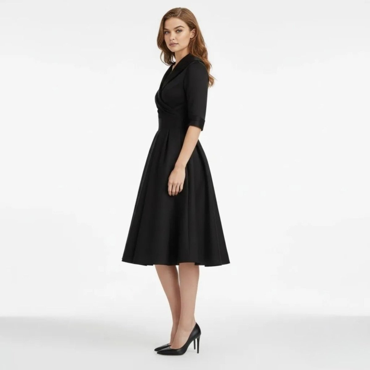 Side profile of a model in the Kouvr Jenner black A-line midi dress, showcasing the full pleated skirt and three-quarter sleeves.