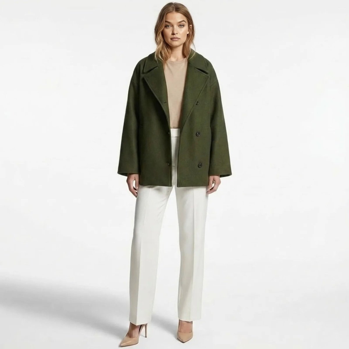 Model wearing the Kouvr Katherine oversized green wool coat, styled open with white trousers and a neutral top.
