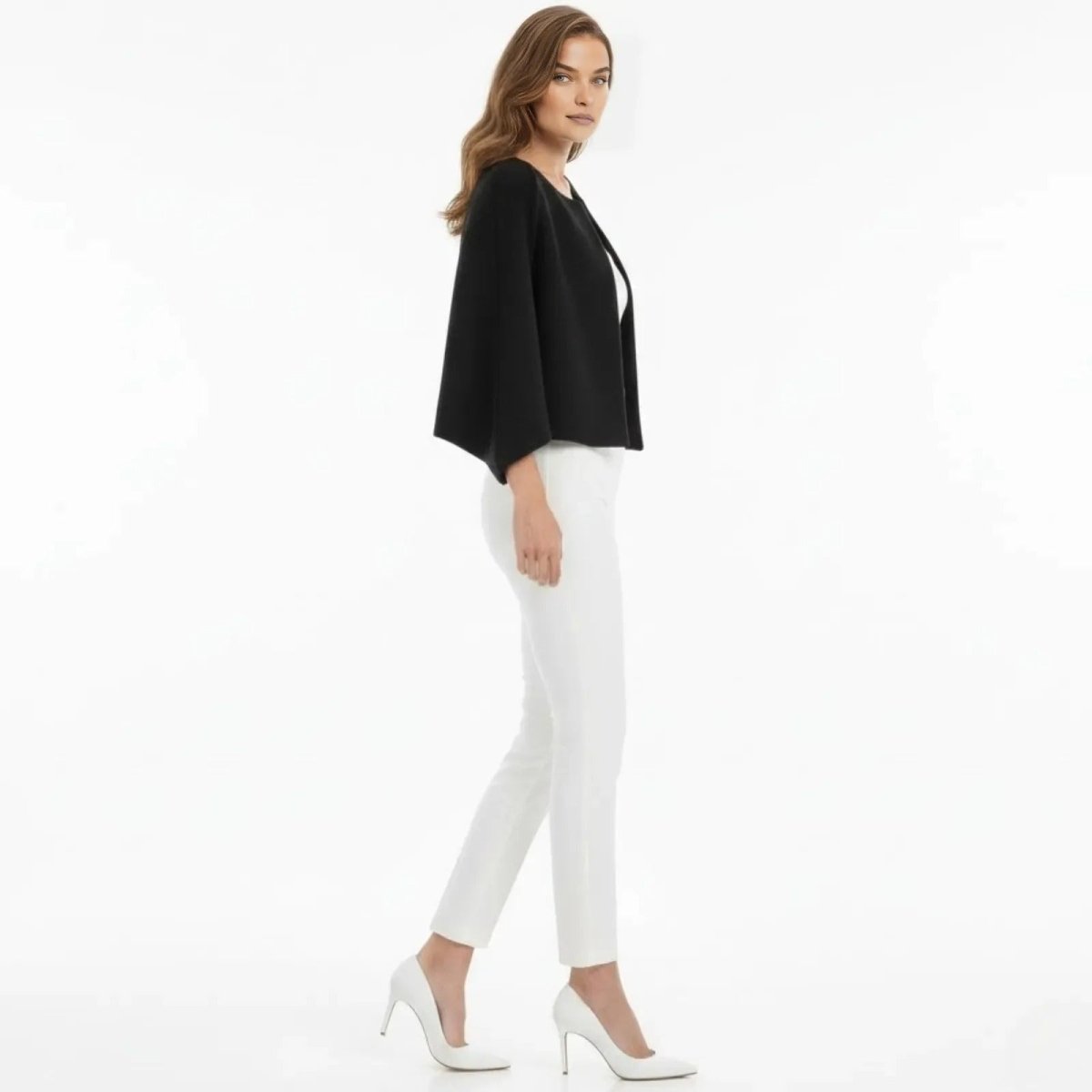 Side profile of a woman wearing the Kouvr Laverne elegant black capelet, showing its silhouette and open sleeve design.