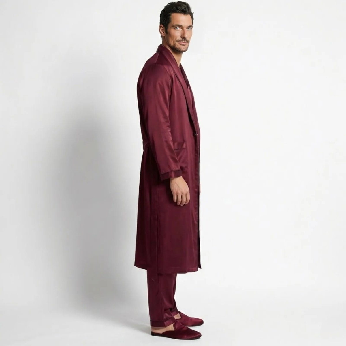 Male model in a Kouvr burgundy silk robe and pajama set, shown from the side profile.