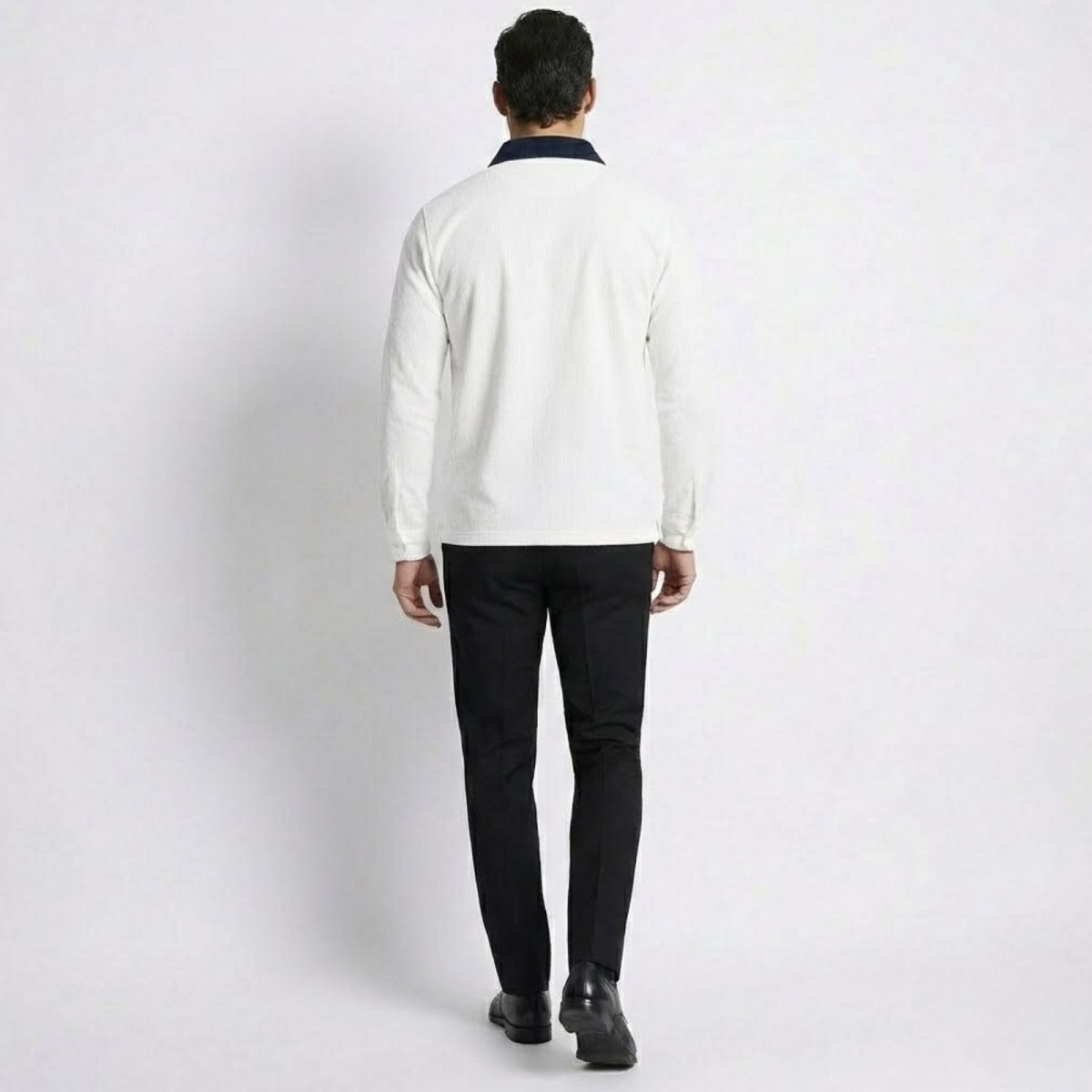 Back view of a model wearing the Kouvr men's white corduroy long sleeve polo with a prominent navy collar.
