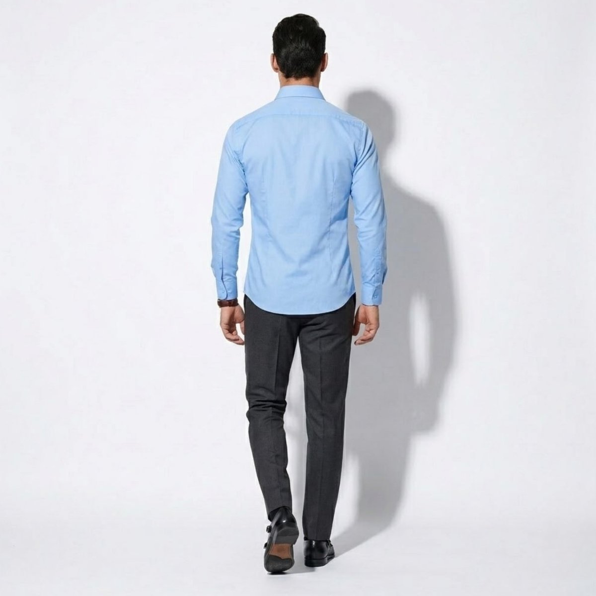 Back view showing the tailored fit of the Kouvr sky blue men's dress shirt on a model.