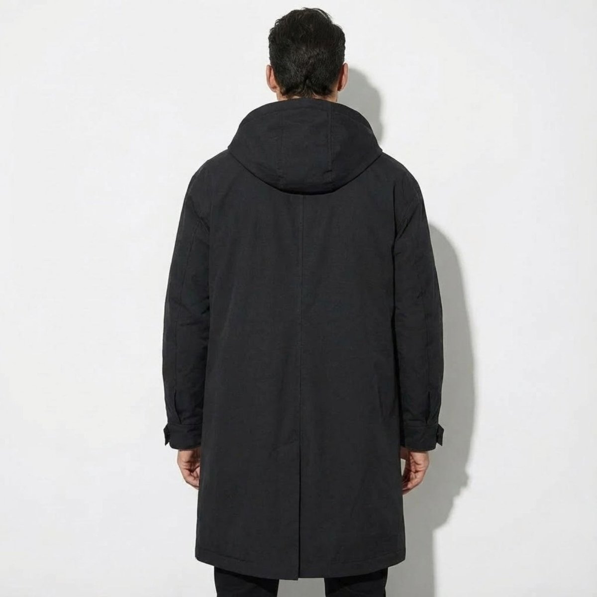 Back view of the black Kouvr all-weather hooded coat, displaying the hood and minimalist design.
