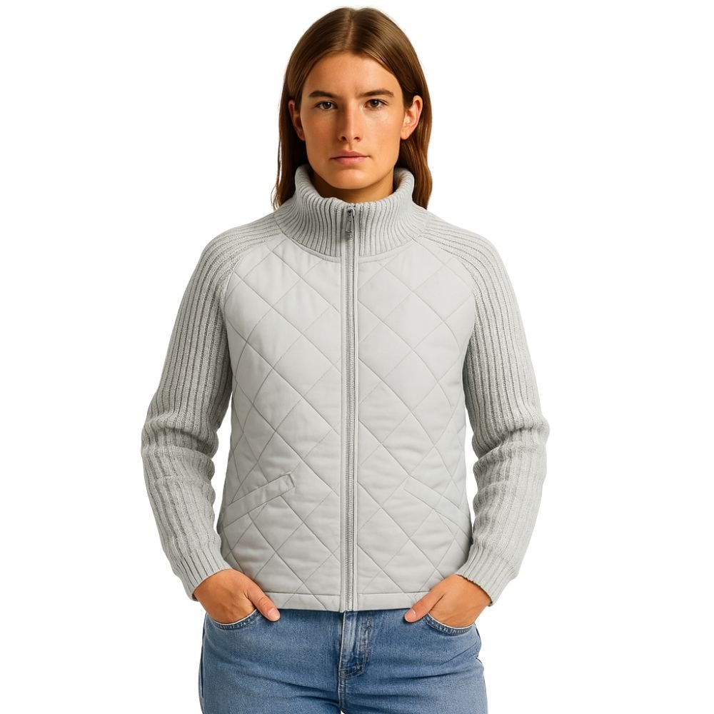 Model wearing the light gray Mika Hybrid Knit Puffer Jacket by Kouvr, zipped up to show the funnel neck and quilted front.
