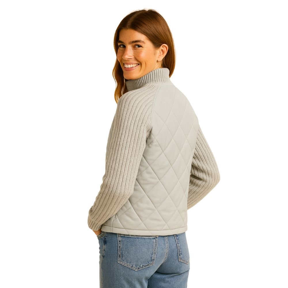 Side profile of a model smiling in the Kouvr Mika Hybrid Jacket, showing the slim fit and texture of the knit sleeves.
