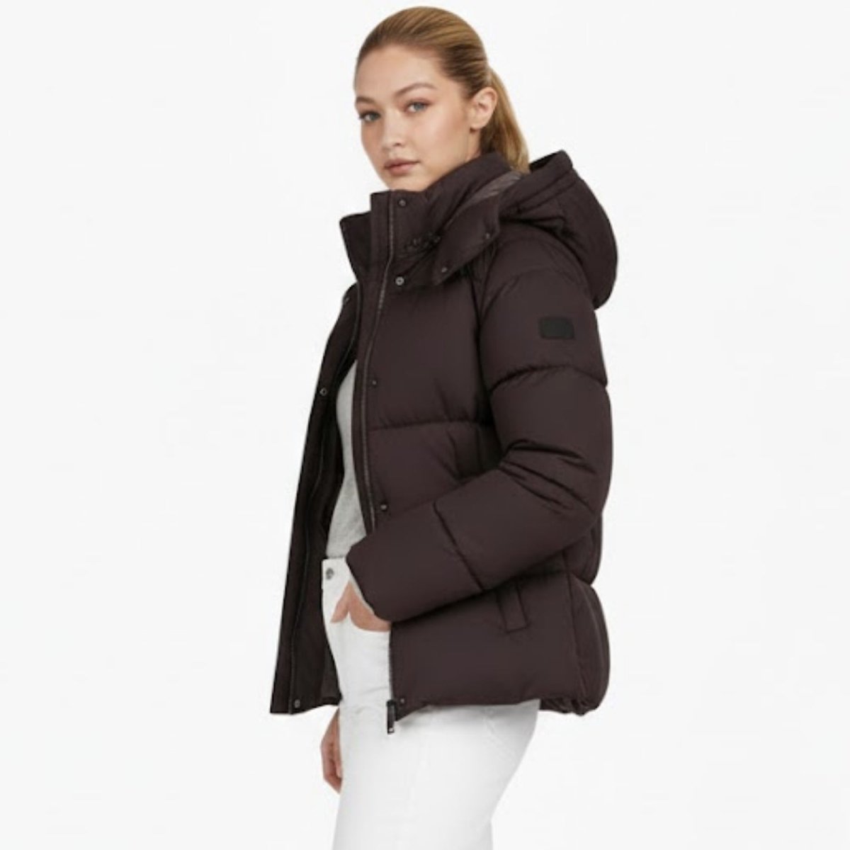 Side profile of a woman in the Kouvr Miranda puffer jacket in espresso brown, showcasing the oversized hood and silhouette.
