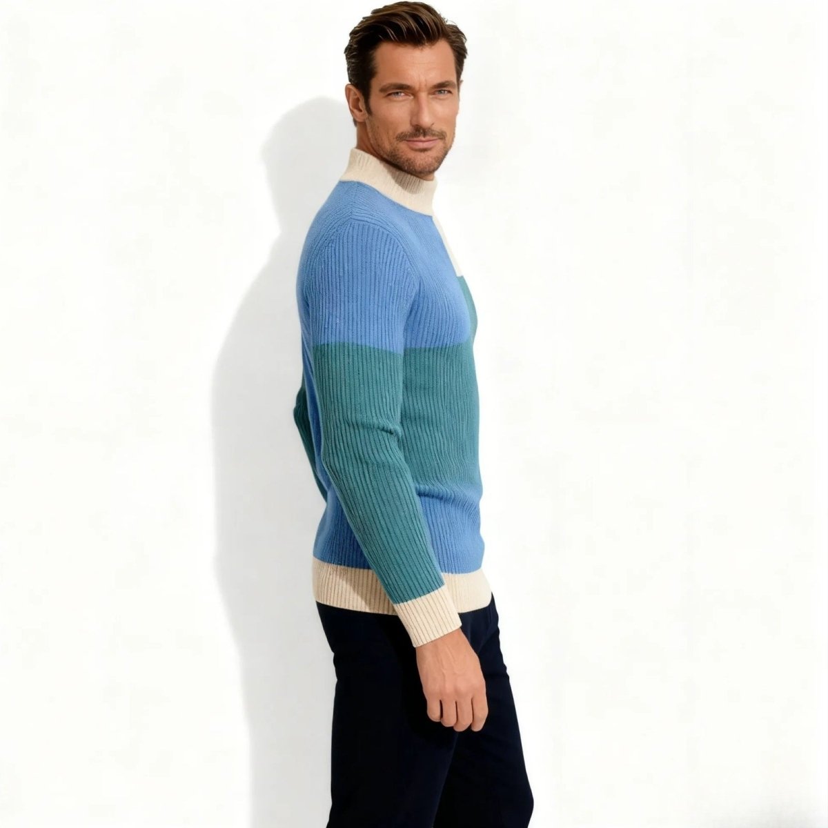 Side profile of a man in a slim fit Kouvr Nerthus  ribbed knit sweater showing the color block pattern on the sleeve and body. 