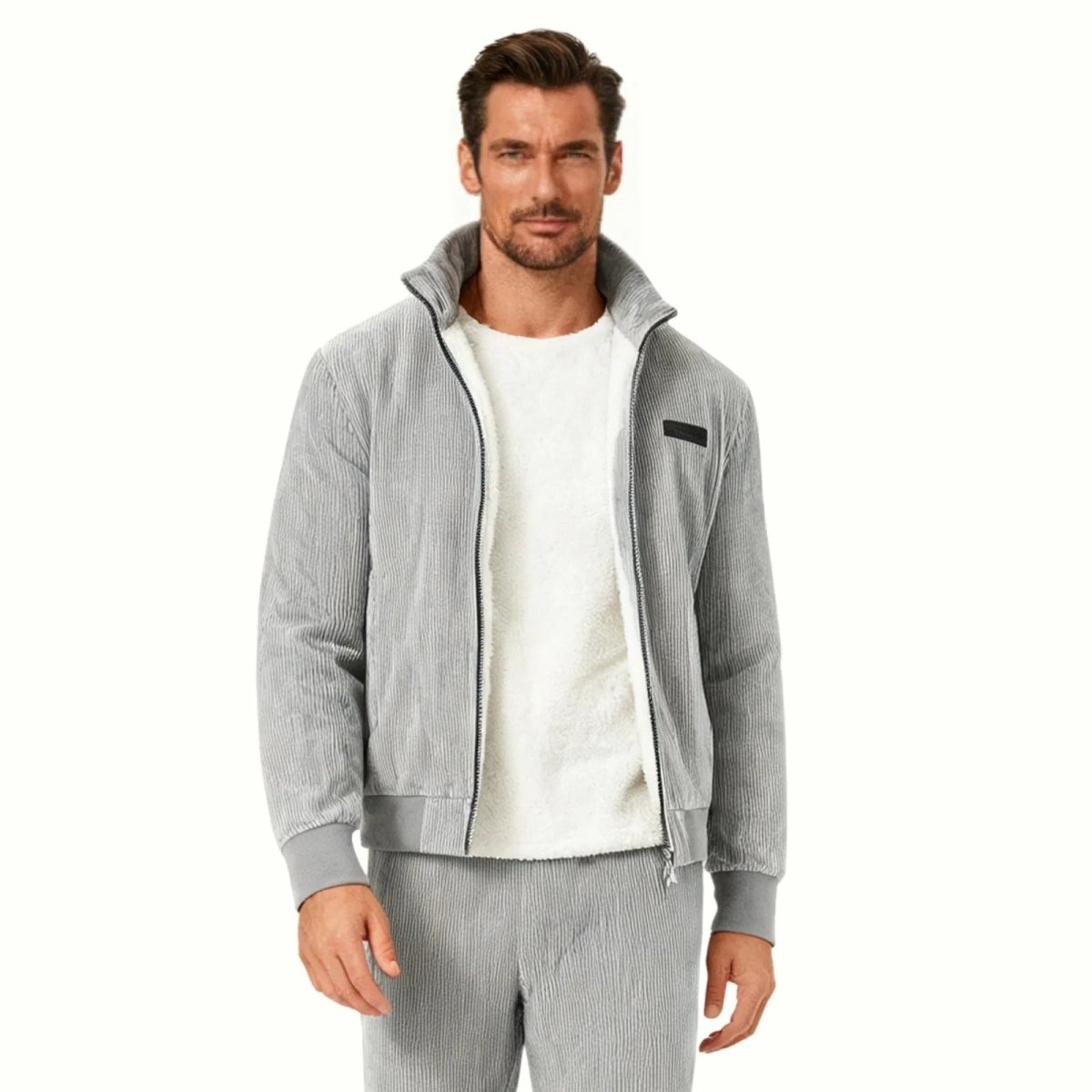 Man wearing a grey corduroy jacket with a white shearling lining and a stand collar, paired with matching grey corduroy pants.