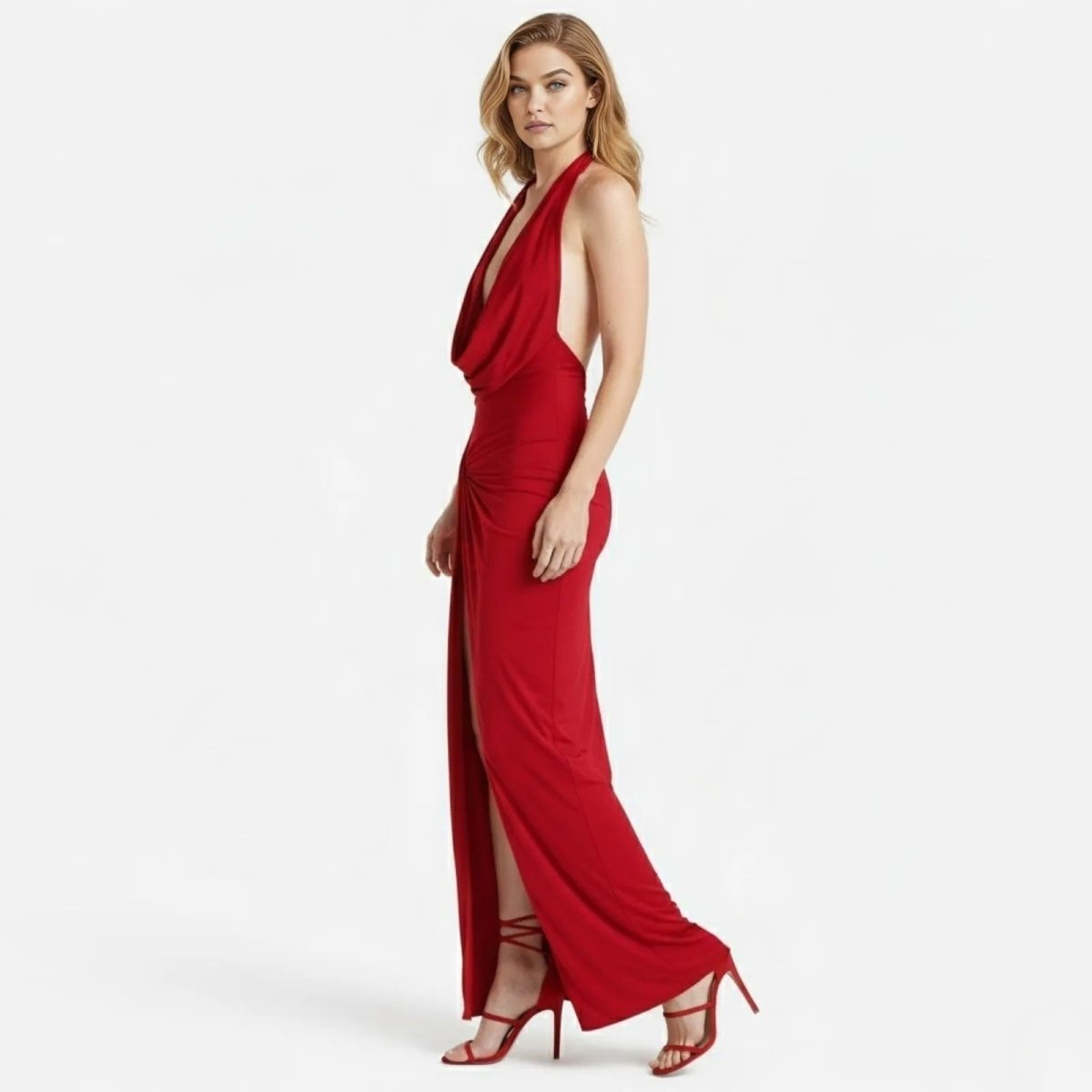Side profile of a model in the Kouvr Nina red halter gown, highlighting the open back design and the flow of the slinky jersey fabric.
