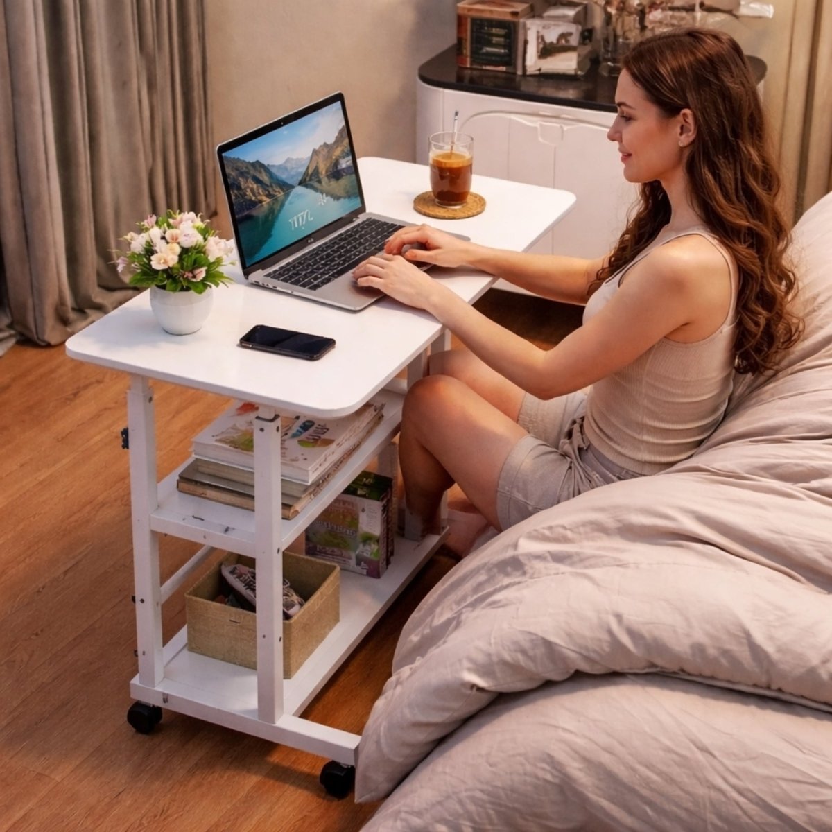 A woman sitting comfortably in bed using a laptop placed on the white Kouvr overbed table, which is adjusted for a perfect working height.