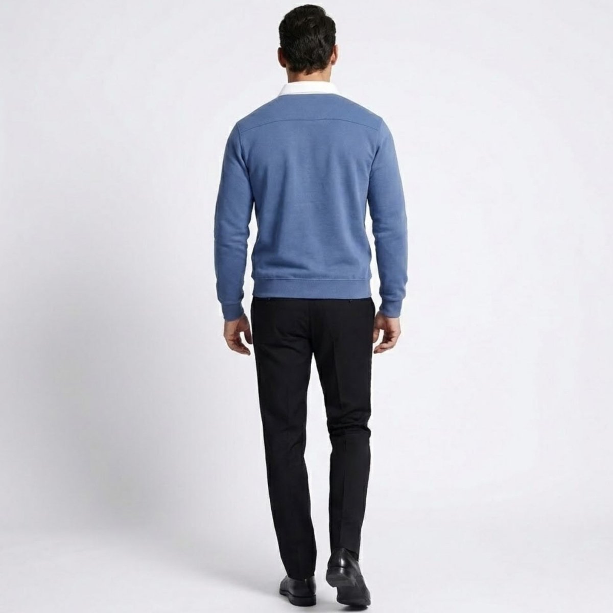 Back view of a man in the Kouvr Rhodes polo sweater, showing the shoulder yoke detail and the clean lines of the garment.
